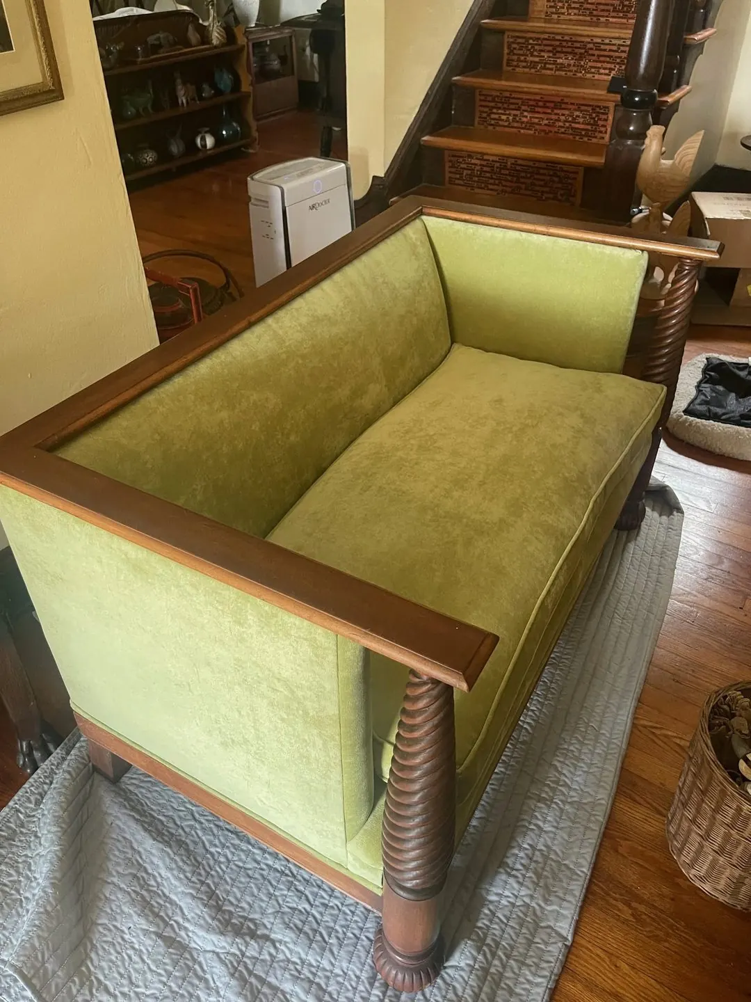 A wood-framed settee with spiral-turned legs, upholstered in green velvet.