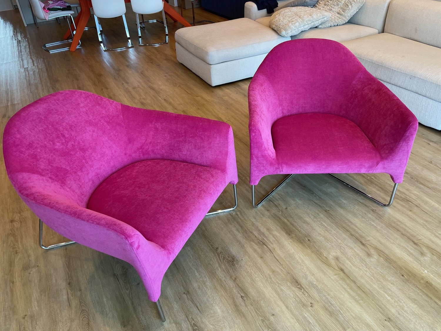 Two curved lounge chairs on chrome sled bases, upholstered in magenta velvet.