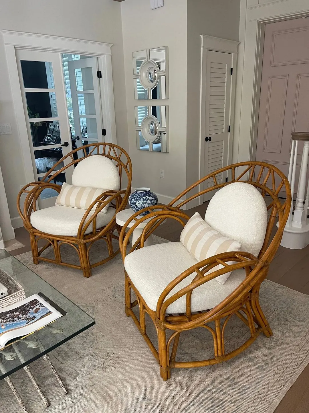 Two bentwood rattan lounge chairs with cream seat and back cushions and striped lumbar pillows.